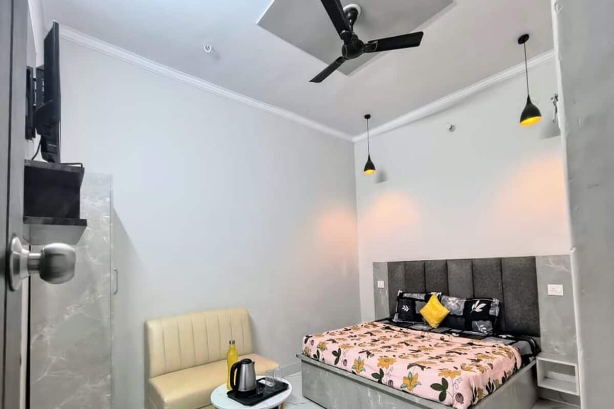 Una camera da letto moderna con un letto, un divano, un tavolino, una ventola a soffitto e una TV.