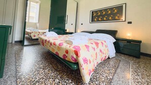 Ein Hotelzimmer mit einem großen Bett, einem spiegelnden Wandbild mit grünem Rahmen, einem Kunstwerk an der Wand und einem Nachttisch in Grün.
