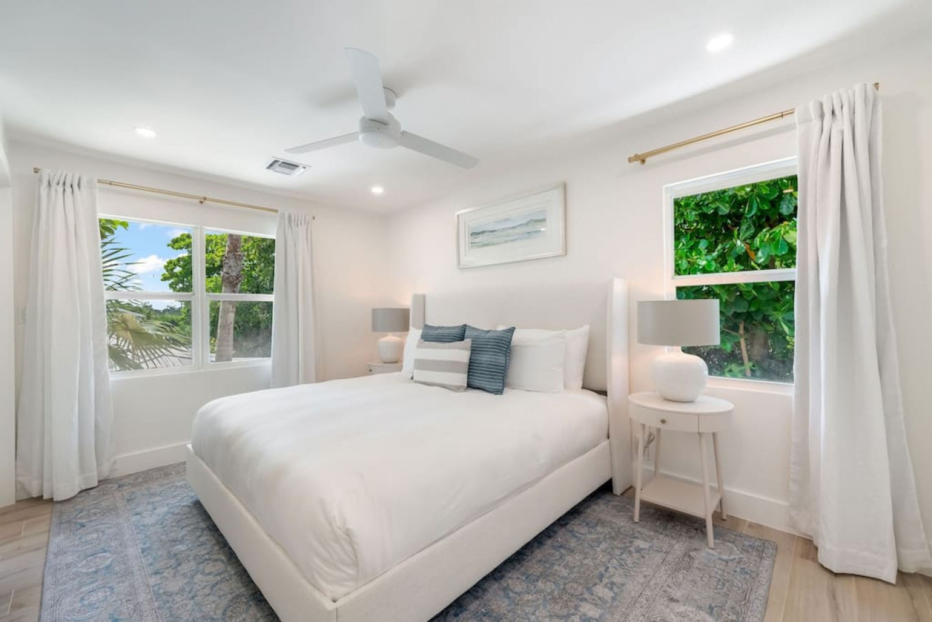 A spacious bedroom with a large bed, two bedside tables with lamps, and a ceiling fan.