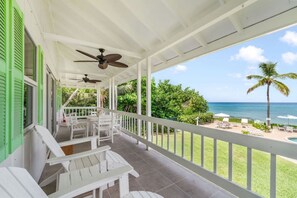 Un espacio exterior cubierto con muebles blancos, una piscina y vistas al océano.