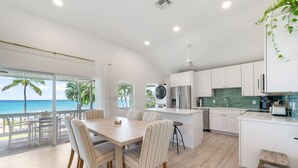 Una cucina moderna con mobili bianchi, un'isola centrale e vista sull'oceano.