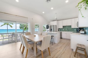 Cozinha moderna com armários brancos, uma ilha central e vista para o oceano.