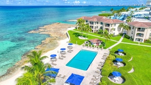 A resort with a pool, beach, and ocean views. - George Town Villas 117 (Seven Mile Beach)