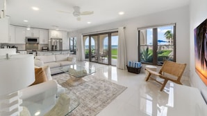 A modern living room with a glass coffee table, white sofas, and a view of the ocean through large windows. - George Town Villas 117 (Seven Mile Beach)