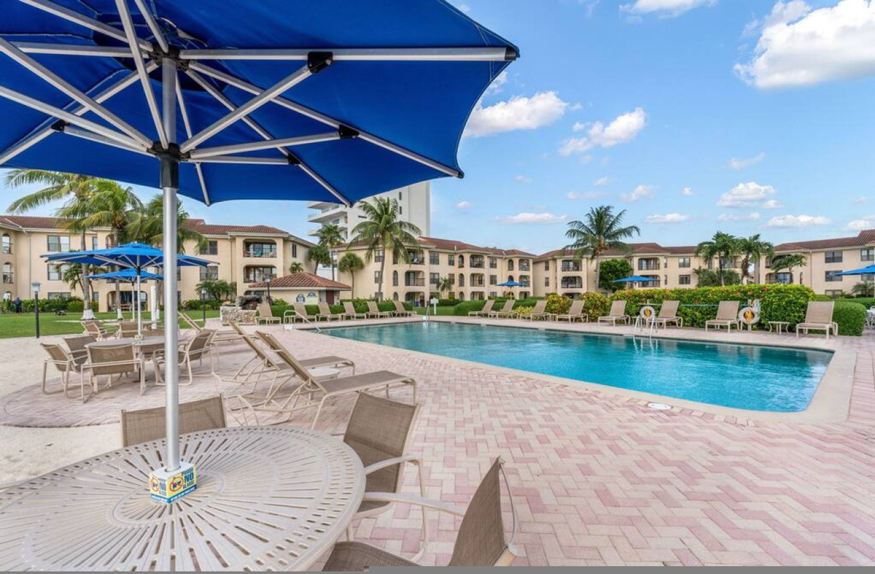 Ein Poolbereich mit Liegestühlen und Sonnenschirmen, umgeben von Hotelgebäuden.