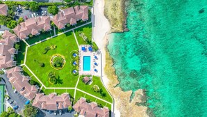 Luftaufnahme eines Resorts mit Schwimmbad, mehreren Gebäuden und einem Strand.
