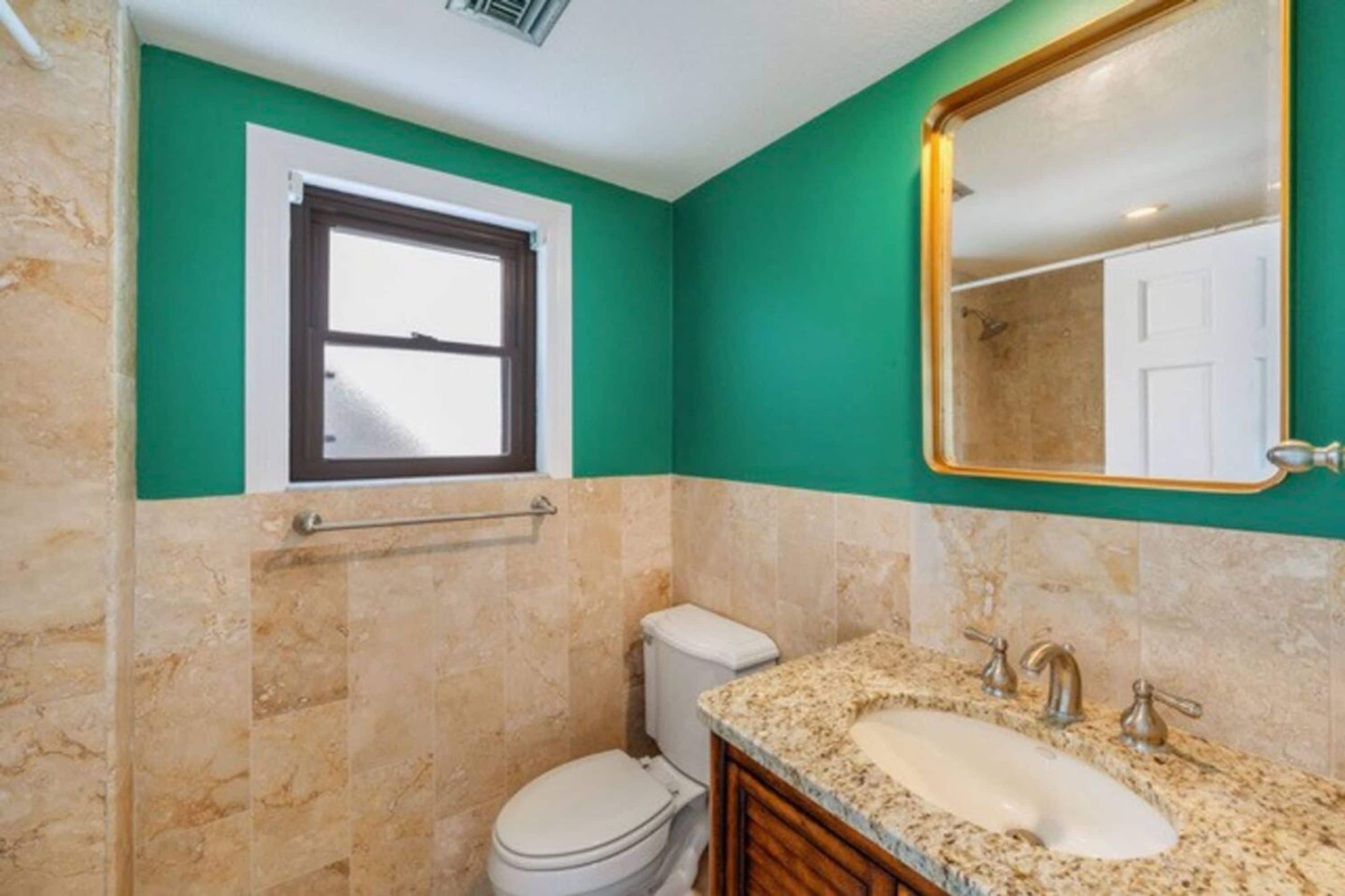 Ein Badezimmer mit Toilette, Waschbecken und Fenster.