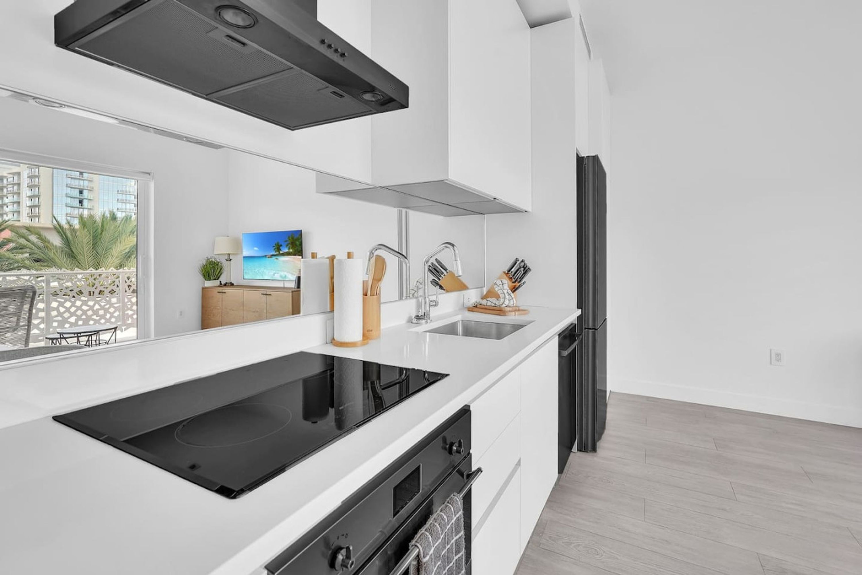 Une cuisine moderne dotée d’une plaque de cuisson à induction noire, d’un évier en acier inoxydable et d’une hotte noire.