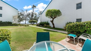 A courtyard with a swimming pool, green chairs, and white buildings with blue trim.
