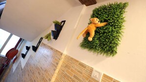A plush toy on a wall, a potted plant, and a tiled floor.