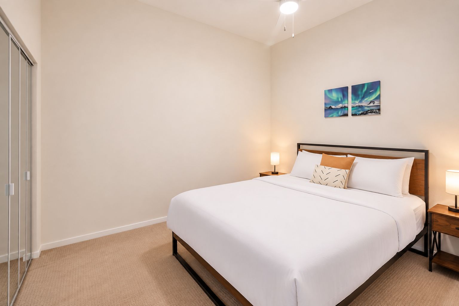 A hotel room with a bed, bedside tables, and a wall-mounted artwork.