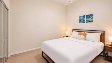 A hotel room with a bed, bedside tables, and a wall-mounted artwork.