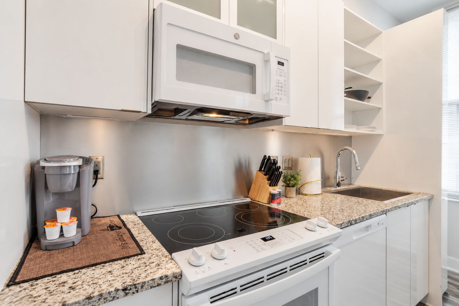 Una cocina moderna con microondas integrado, cafetera, fregadero y estufa.