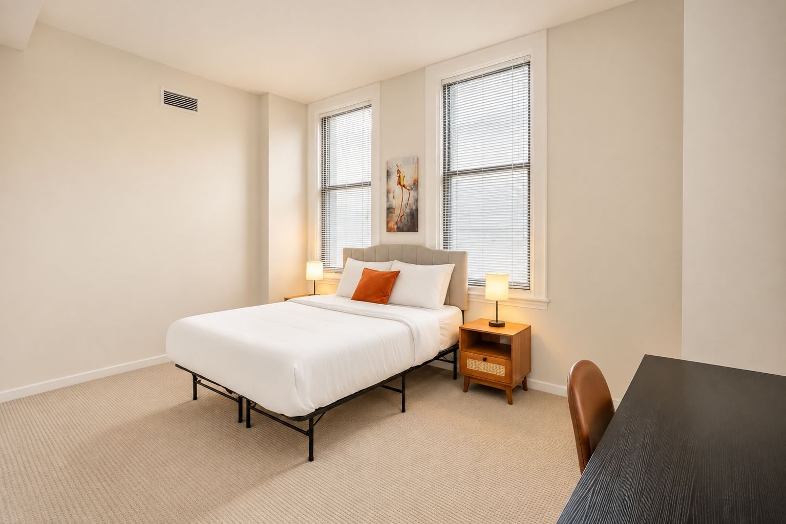 Un dormitorio con cama, mesitas de noche, lámpara, una silla y ventana.