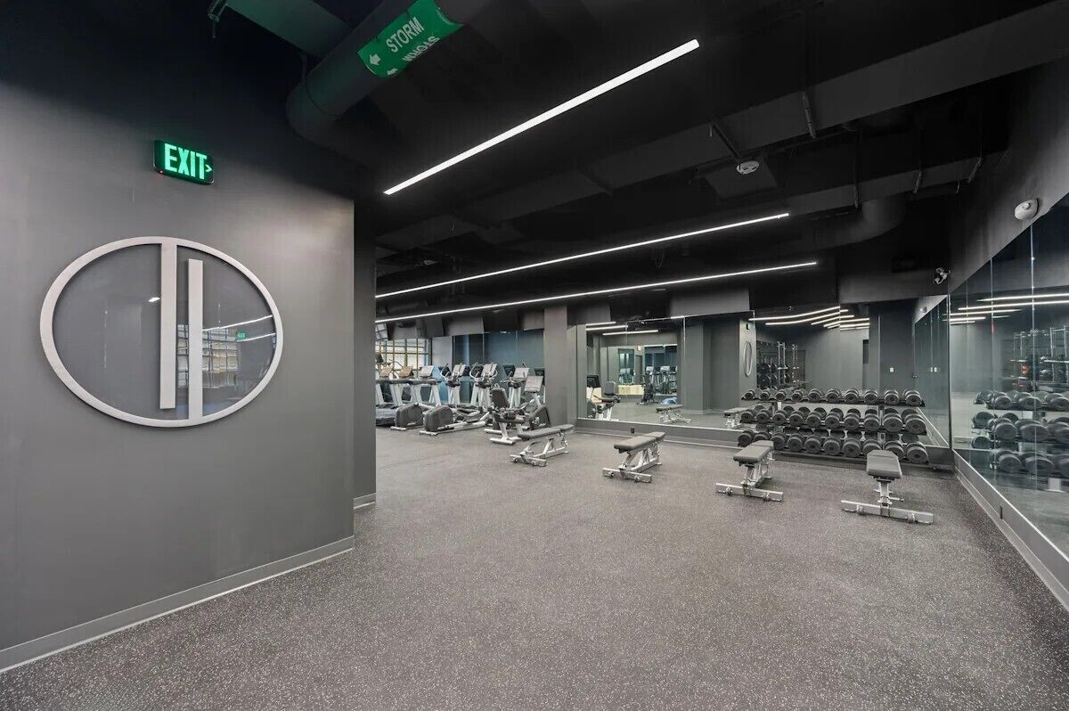 Un gimnasio moderno con máquinas de cardio, pesas libres y bancos.