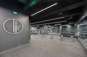 Un gimnasio moderno con máquinas de cardio, pesas libres y bancos.