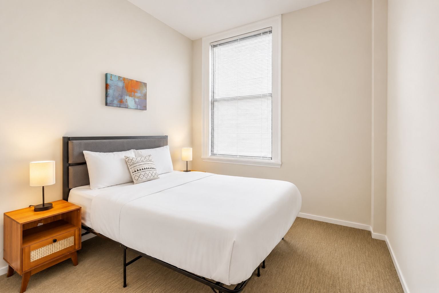 A neatly made bed with white bedding, a gray headboard, and two bedside lamps on wooden nightstands.