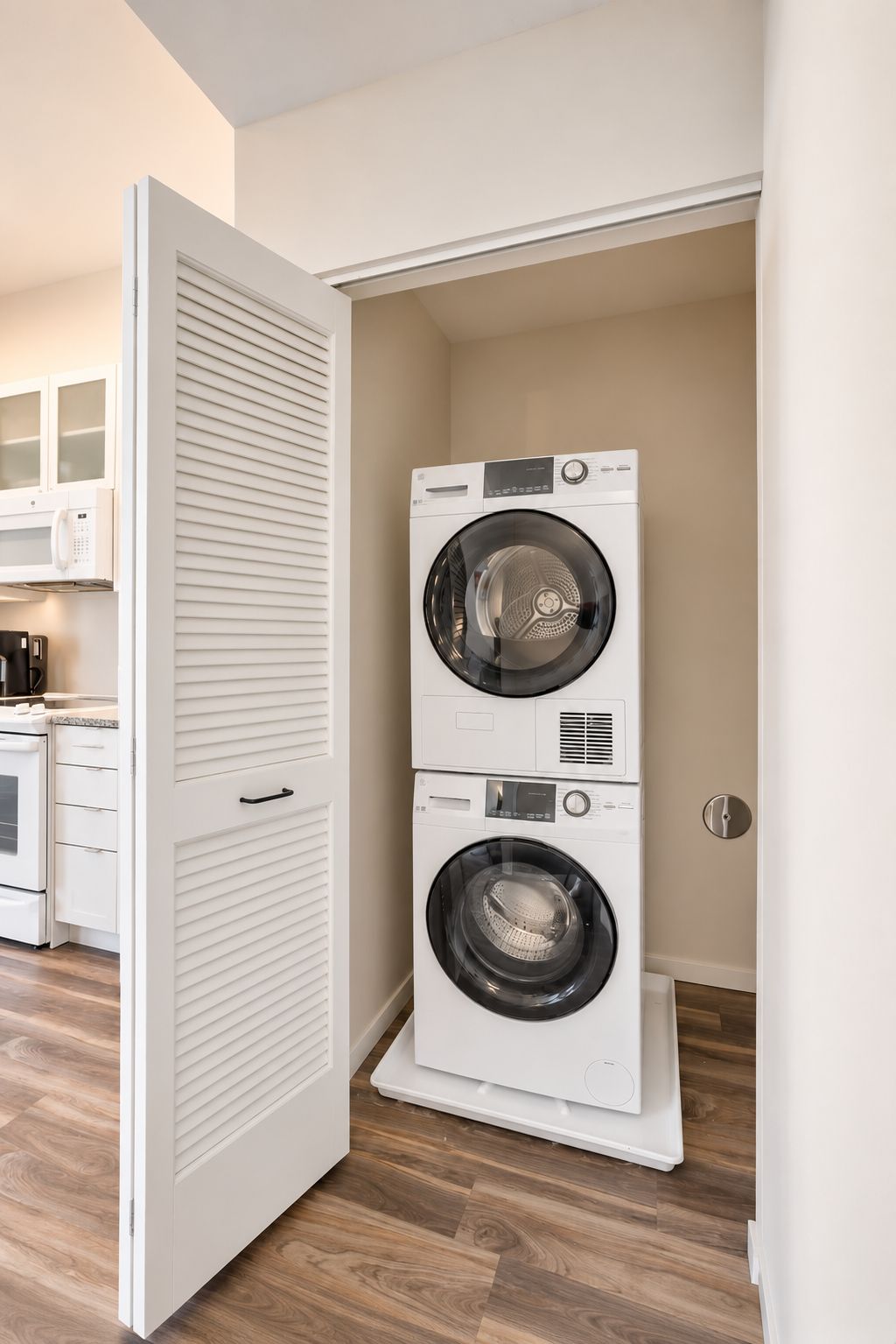 A laundry room with two stacked front-loading washing machines, a microwave, and a stove.