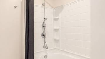 A modern bathroom with a freestanding bathtub, a showerhead, and a towel rack.