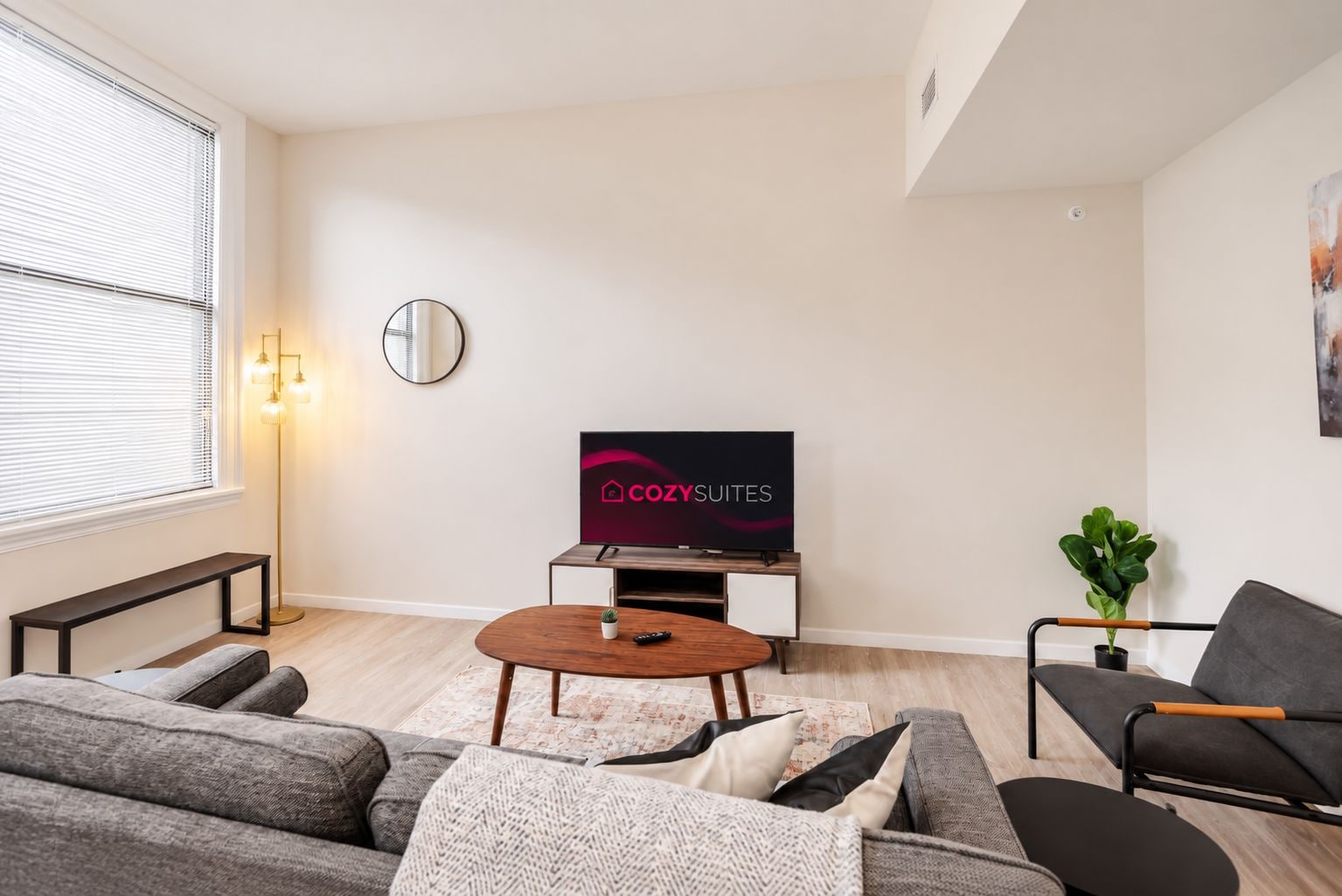 Un salon moderne avec un téléviseur à écran plat, une table basse ronde et deux canapés.