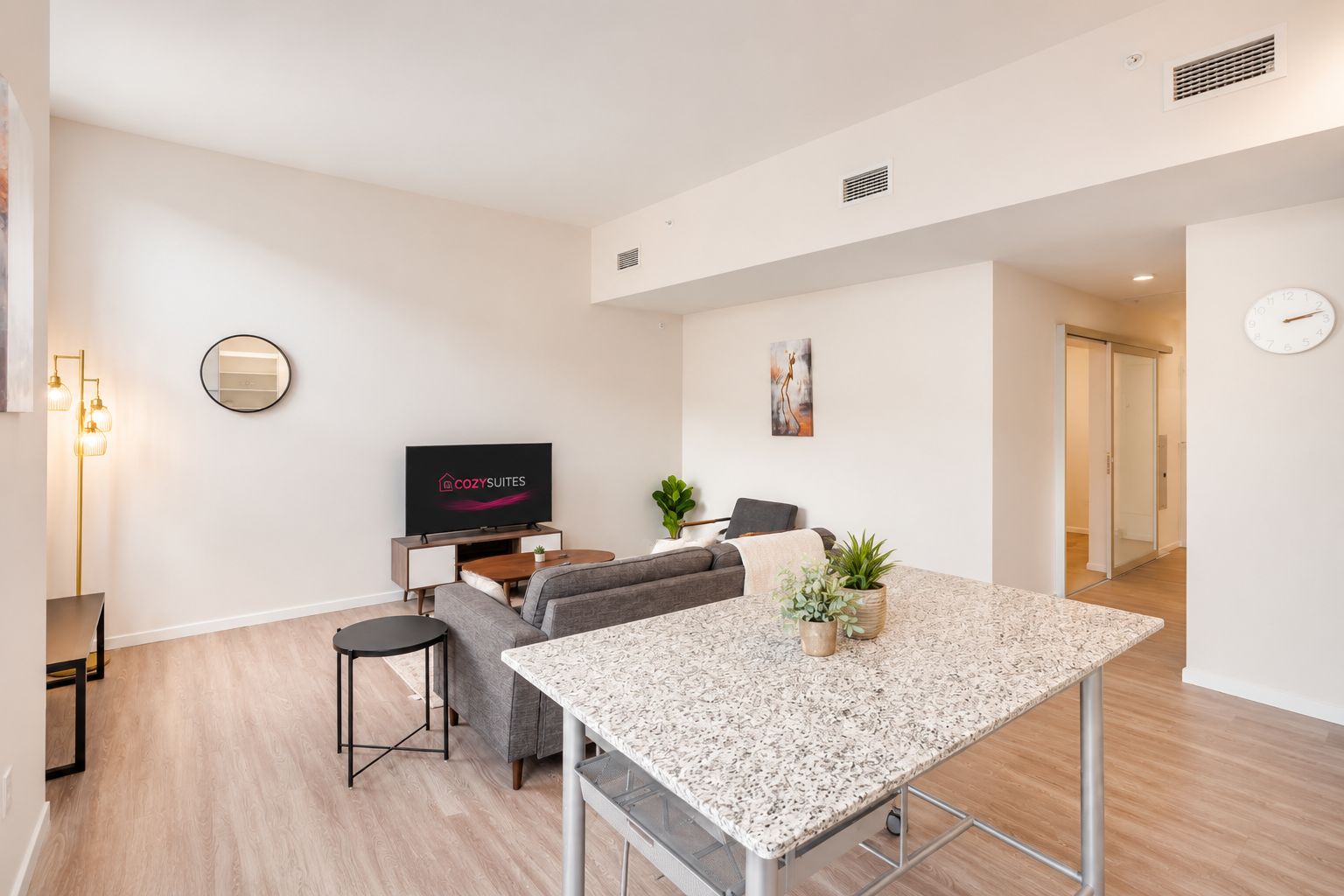 A modern living room with a flat-screen TV, a sofa, a coffee table, and a dining table.