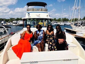 Un groupe de personnes se trouve sur un bateau doté d’une cabine et offrant une vue sur les autres bateaux amarrés dans la marina.