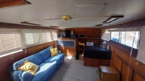 Interior compacto de autocaravana con sofá azul, una kitchenette pequeña y una ventana que proporciona luz natural.