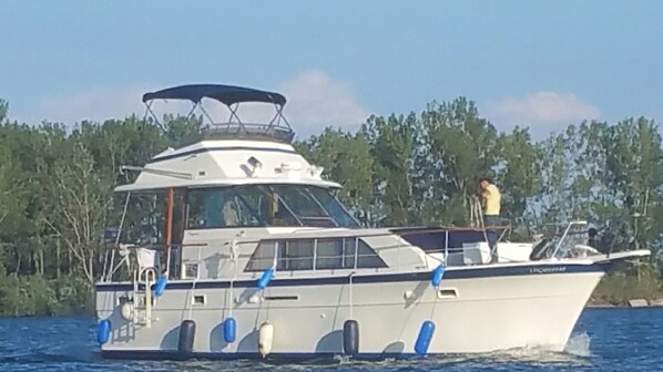A boat with a covered deck area, a cabin, and a person standing on the deck.