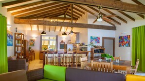 A spacious living area with a high ceiling, wooden beams, a dining table, and a sofa. - Tahaa - Villa Tehere Dream Beach Front (Taha'a)