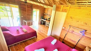 Une cabane en bois avec deux lits, une petite table et une étagère contenant des articles de toilette.
