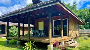 Une cabane en bois dotée d’un porche abrité, de meubles d’extérieur et offrant une vue sur la verdure environnante.
