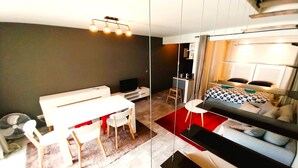 A modern, compact living space with a dining area, a bed with a geometric-patterned duvet, and a television. - Tahiti - Urban Escape (Papeete)