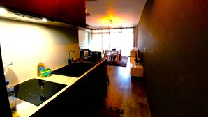 A compact kitchen with a central island, a dining area with a table and chairs, and a view of the outdoors through a window. - Tahiti - Urban Escape (Papeete)
