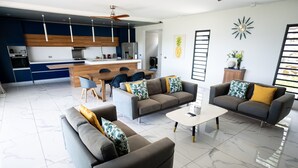 Una sala de estar moderna con comedor, cocina y un amplio ventanal con persianas.