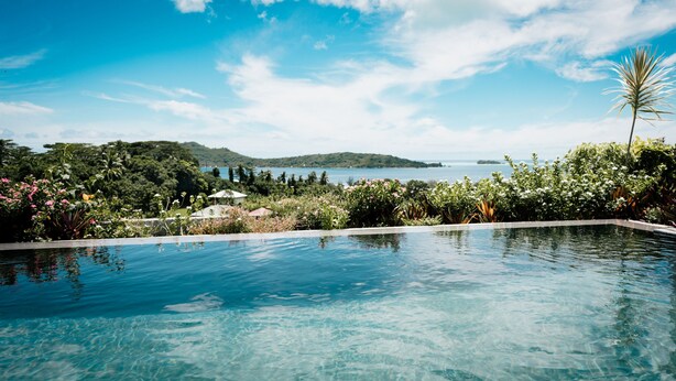 Vista despejada de una piscina con vistas a un lago y colinas al fondo.