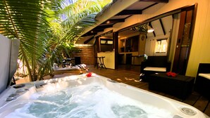 Un bain à remous doté de jets d’eau, entouré de chaises longues et d’une terrasse en bois.
