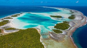 An aerial view of a coastal area with clear turquoise waters, sandy beaches, and lush green vegetation. - Rangiroa - My Eden Place (Rangiroa)