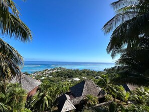 A tropical resort with thatched-roof buildings, lush greenery, and a view of the ocean. - Moorea - Villa Ana Mua (Moorea-Maiao)