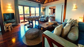 A spacious living area with a foosball table, a television, and a large window providing natural light. - Moorea - Villa Ana Mua (Moorea-Maiao)