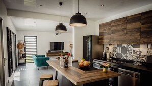 Une cuisine moderne avec un îlot central en bois, des luminaires suspendus et un grand réfrigérateur.