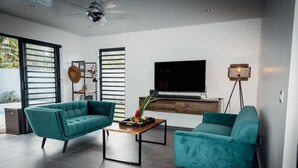 Un salon moderne avec des canapés de couleur turquoise, une table basse en bois, un téléviseur à écran plat et un lampadaire.