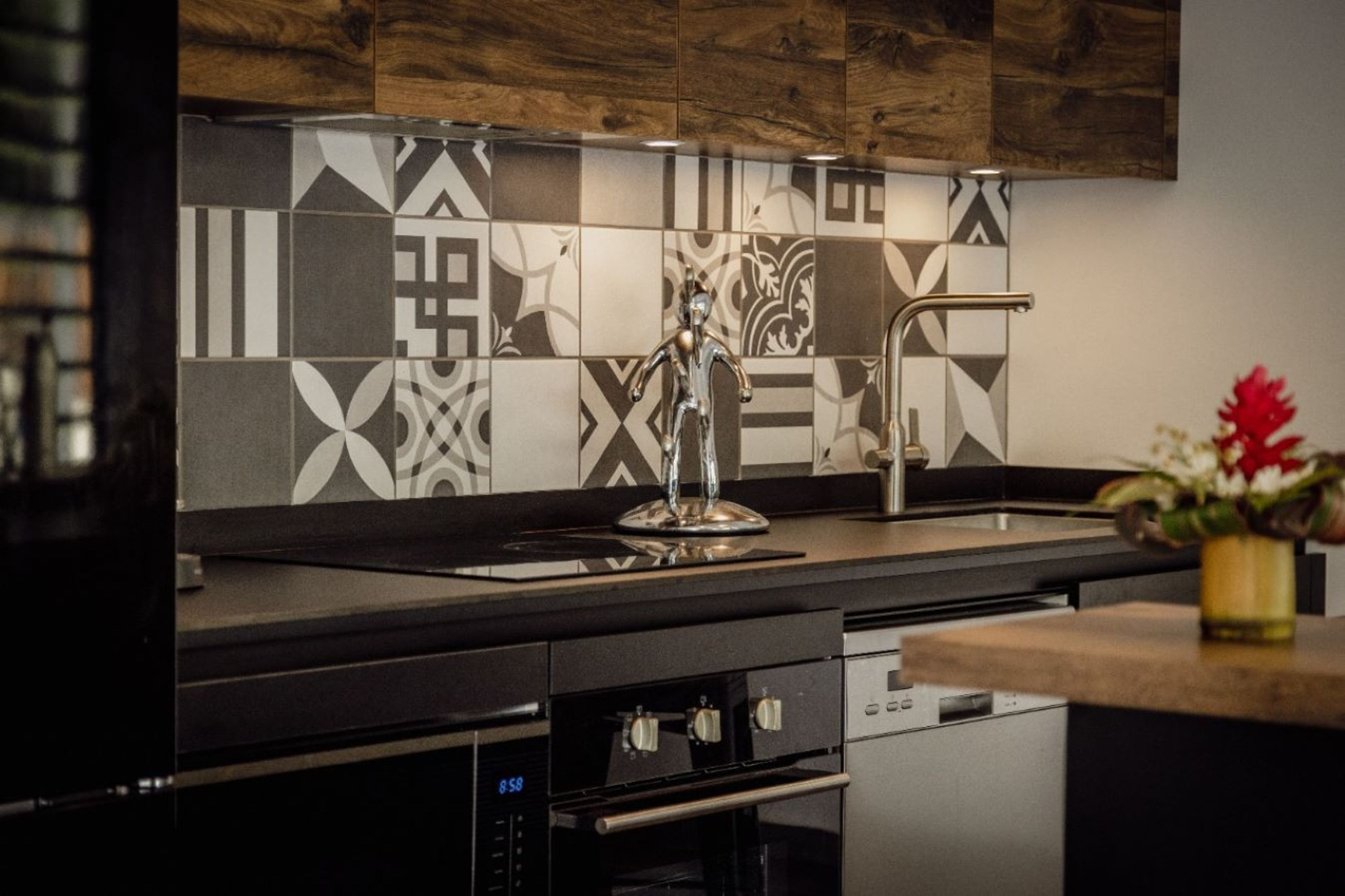 A modern kitchen with a patterned backsplash, stainless steel appliances, and a wooden cabinet.