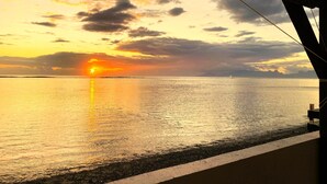 A sunset over a calm sea viewed from a covered area with a clear horizon. - Tahiti - The Cozy Corner (Paea)