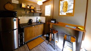A compact kitchen with a refrigerator, stove, sink, and bar stools. - Moorea - Tropical Nest (Moorea-Maiao)