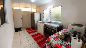 A compact kitchen with a refrigerator, stove, and sink. - Tahiti - Matavai Bay Cottage (Arue)