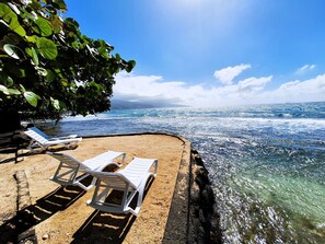 Une plage avec deux chaises longues blanches et une vue dégagée sur l’océan.