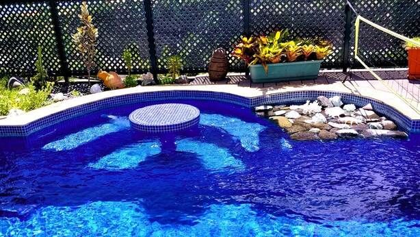A swimming pool with clear blue water, surrounded by a tiled deck and various plants. - Tahiti - Terevete Pool Studio (Arue)