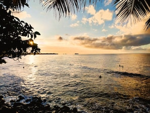 A beach scene with calm waters, a sunset, and distant land. - Tahiti - Haumaru Beach Fare (Mahina)