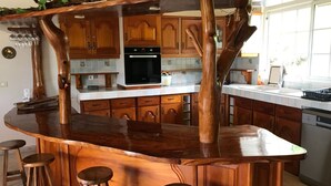 Una cocina con isla central, armarios de madera, horno empotrado y taburetes de bar.