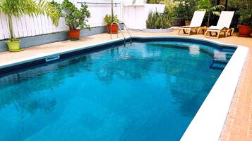 Relax by the pool surrounded by lush greenery and comfortable lounge chairs.